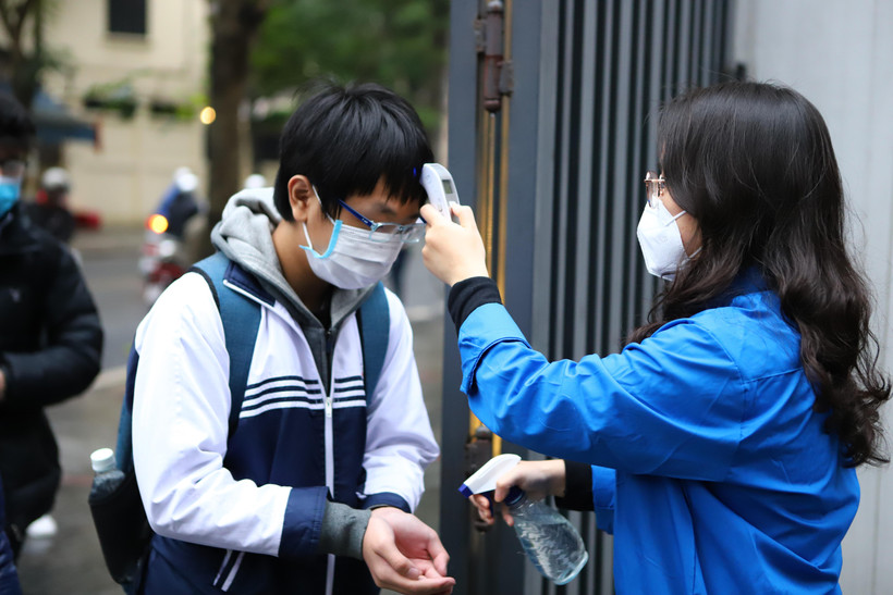 Học sinh được đo thân nhiệt, sát khuẩn trước khi vào lớp. (Ảnh: Nguyễn NamVietnam+)