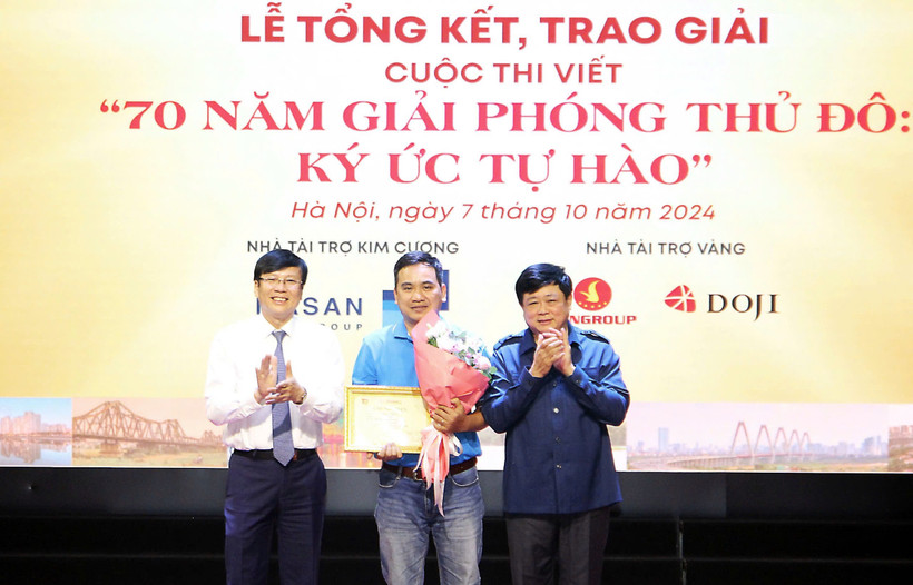 Ông Nguyễn Thế Kỷ, Chủ tịch Hội đồng Lý luận, phê bình văn học nghệ thuật Việt Nam (bìa phải) cùng ông Hồ Quang Lợi, Phó Chủ tịch Hội Truyền thông số Việt Nam trao giải Nhất cho tác giả Đan Nhiễm. (Ảnh: PV/Vietnam+)