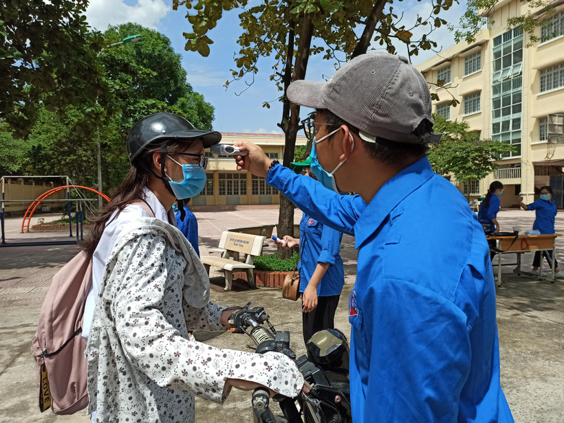 Thí sinh được kiểm tra thân nhiệt trước khi vào điểm thi. (Ảnh: Phạm Mai/Vietnam+)