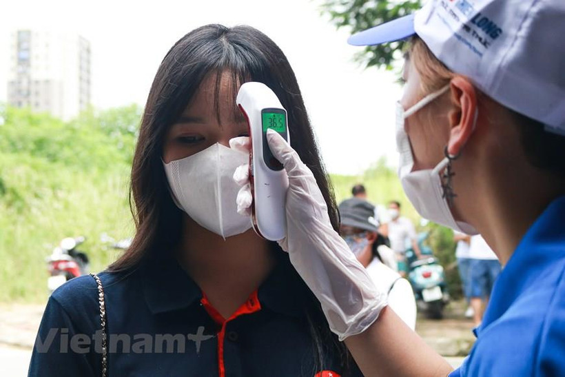 Tất cả các thí sinh đều được kiểm tra thân nhiệt trước khi vào điểm thi. (Ảnh: Vietnam+)