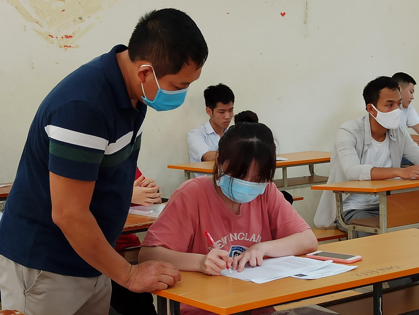 Thí sinh và giám thị cùng đeo khẩu trang vào phòng thi trong kỳ thi Tốt nghiêp Trung học phổ thông 2020. (Ảnh: Phạm Mai/Vietnam+)