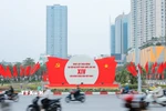 Khẩu hiệu, biểu trưng Đại hội nổi bật giữa dòng xe qua lại trên đường phố Hà Nội. (Ảnh: Lê Đông/TTXVN)