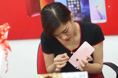 Dán bảo vệ cho siêu phẩm của "quả táo" tại FPT Shop. (Ảnh: Trung Hiền/Vietnam+)