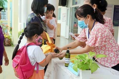 Giáo viên Trường Mầm non Tuổi thơ (Quận 8) hướng dẫn trẻ rửa tay trước khi vào lớp. (Ảnh: Thu Hoài/TTXVN)