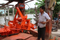 Ông Dương Quốc Thái vận hành thử máy đắp bờ. (Ảnh: Minh Trí-TTXVN)