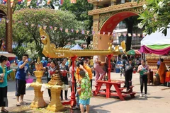 Trẻ nhỏ lấy nước tắm Phật xoa lên đầu người lớn để cầu chúc gặp nhiều may mắn. (Ảnh: Xuân Tú/TTXVN) 