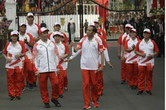 Tổng thống Indonesia Joko Widodo (giữa) cầm ngọn đuốc Thế vận hội châu Á và Bộ trưởng Thanh niên và Thể thao Imam Nahrawi (trái) trong buổi lễ Ngày Độc lập tại Cung điện Merdeka ở Jakarta, ngày 17/8/2018. (Nguồn: AP)