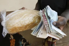 Người dân trả tiền để mua bánh mì tại Harare, Zimbabwe. (Ảnh: AFP/ TTXVN)