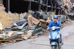 Người dân sinh sống tại đây phải đeo khẩu trang mỗi khi đi qua khu vực cháy nhà máy Bóng đèn Phích nước Rạng Đông. (Ảnh: Thành Đạt/TTXVN)