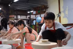 Các em nhỏ trong dịp nghỉ Hè được trải nghiệm thực tế làm sản phẩm gốm tại Bát Tràng. (Ảnh: Hoài Nam/Vietnam+)