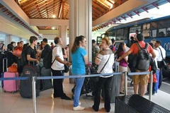 Hành khách đợi xe buýt tại sân bay Bali ngày 28/11. (Nguồn: Kyodo/TTXVN)