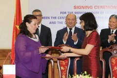 Bà Nguyễn Thị Hảo, Phó Cục trưởng Cục Con nuôi (Bộ Tư pháp Việt Nam) và bà Carmen Buttigieg, Vụ trưởng Vụ Tiêu chuẩn phúc lợi xã hội, Bộ Gia đình và Đoàn kết Xã hội (Cộng hòa Malta) trao đổi Bản ghi nhớ. (Ảnh: Doãn Tấn/TTXVN) 