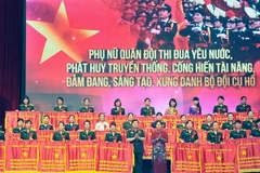 Thượng tướng Ngô Xuân Lịch và Chủ tịch Hội Liên hiệp Phụ nữ Việt Nam Nguyễn Thị Thanh Hòa tặng Cờ Thi đua của Tổng cục Chính trị cho các gương phụ nữ điển hình tiên tiến. (Ảnh: Trọng Đức/TTXVN)