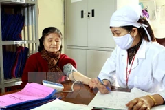 Nhân viên y tế kiểm tra sức khỏe cho người dân. (Ảnh: TTXVN)