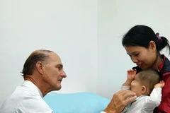 Bác sỹ McKay McKinnon khám lâm sàng cho một trẻ em bị dị dạng hốc mắt. (Ảnh: TTXVN phát)