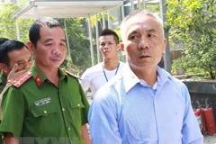 Cảnh sát dẫn giải các bị cáo trong đường dây tổ chức mang thai hộ vì mục đích thương mại. (Ảnh: Doãn Tấn/TTXVN) 