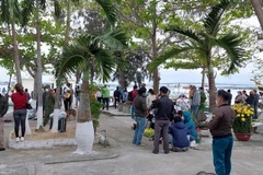 Người dân theo dõi lực lượng chức năng tìm kiếm nạn nhân mất tích tại Cửa Đại. (Ảnh: TTXVN)