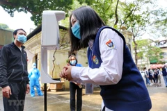 Học sinh đo thân nhiệt và sát khuẩn tay trước khi vào lớp. (Ảnh: Tuấn Đức/TTXVN)