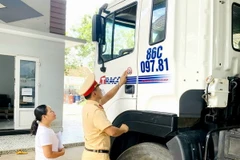 Lực lượng cảnh sát giao thông tiến hành dán Logo decal với nội dung “Đã uống rượu bia-Không lái xe” lên các phương tiện vận tải là thành viên của Hợp tác xã vận tải ôtô Phan Thiết. (Ảnh: Nguyễn Thanh/TTXVN)