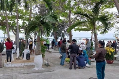 Người dân theo dõi lực lượng chức năng tìm kiếm nạn nhân mất tích tại Cửa Đại. (Ảnh: TTXVN)