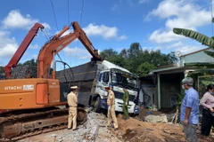 Lực lượng chức năng sử dụng xe chuyên dụng cẩu xe tải, khắc phục hậu quả vụ tai nạn. (Ảnh: TTXVN phát)