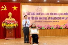 Phó Bí thư Thường trực Tỉnh ủy, Chủ tịch HĐND tỉnh Quảng Trị Nguyễn Đăng Quang trao danh hiệu "Bà mẹ Việt Nam Anh hùng” cho bà Lê Thị Mót, xã Gio Sơn, huyện Gio Linh. (Ảnh: Nguyên Lý/TTXVN)