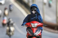 Người dân trang bị khẩu trang, áo chống nắng kín mít vẫn phải giơ tay che mặt vì nắng nóng cộng với tỷ lệ tia cực tím cao. (Ảnh: Thành Đạt/TTXVN)