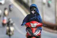 Người dân trang bị khẩu trang, áo chống nắng để ngăn tia cực tím gây hại. (Ảnh: Thành Đạt/TTXVN)