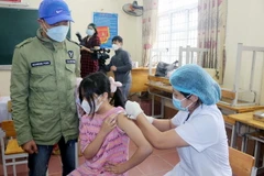 Trẻ em được tiêm tại điểm tiêm trường THCS Lương Khánh Thiện, thành phố Phủ Lý, dưới sự theo dõi của phụ huynh và nhân viên y tế. (Ảnh: Đại Nghĩa/TTXVN)