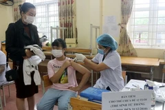 Trẻ được tiêm tại điểm tiêm trường THCS Lương Khánh Thiện, thành phố Phủ Lý, dưới sự theo dõi của phụ huynh và nhân viên y tế. (Ảnh: Đại Nghĩa/TTXVN)