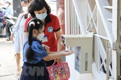Học sinh trường tiểu học Hòa Bình, quận 1, được giáo viên hướng dẫn rửa tay trước khi vào lớp. (Ảnh: Hồng Giang/TTXVN)