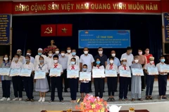 Ông Trương Hòa Bình, nguyên Phó Thủ tướng thường trực Chính phủ cùng các đại biểu và các em học sinh, sinh viên dân tộc thiểu số nhận học bổng. (Ảnh: Thanh Vũ/TTXVN)