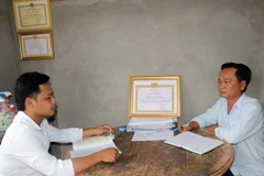 Bí thư ấp Hòa Quới Trần Minh Sơn (phải) trao đổi với cán bộ Tuyên giáo xã về công tác tuyên truyền. (Ảnh: Hữu Chí/TTXVN)