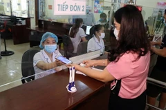 Người dân sử dụng thẻ BHYT điện tử trên ứng dụng VssID để đăng ki khám bệnh. (Ảnh: Hữu Quyết/TTXVN)