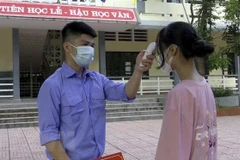 Đo thân nhiệt cho học sinh trước khi vào trường học. (Nguồn: TTXVN)