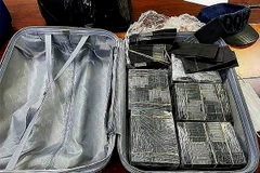 Cơ quan chức năng thu giữ số lượng lớn tiền mệnh giá 100 USD bị nhuộm đen bằng hóa chất. (Ảnh: TTXVN phát)