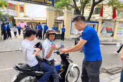 Tình nguyện viên hỗ trợ nước uống cho sỹ tử, phụ huynh tại điểm thi trường Trung học phổ thông Trần Nhân Tông. (Ảnh: PV/Vietnam+)
