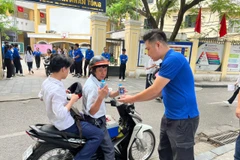 Tình nguyện viên hỗ trợ nước uống cho sỹ tử, phụ huynh tại điểm thi trường Trung học phổ thông Trần Nhân Tông. (Ảnh: PV/Vietnam+)