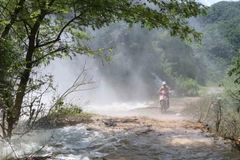 Người dân gặp khó khăn khi đi qua những điểm xuất hiện dòng thác lũ đổ xuống từ vách núi bên đường. (Ảnh: Xuân Tiến/TTXVN)