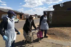 Cảnh sát giúp đỡ một người già trên đường đi mua thực phẩm. (Ảnh: Phi Hùng/TTXVN)