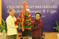 Thay mặt các cựu lưu học sinh Việt Nam từng học tại Trường Đại học Quốc gia Lào, Đại sứ Nguyễn Mạnh Hùng tặng hoa ông Phankham Viphavan, Ủy viên Bộ Chính trị, Phó Thủ tướng Chính phủ, Bộ trưởng Giáo dục và Thể thao Lào. (Ảnh: Phạm Kiên/TTXVN)
