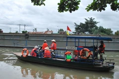 Người dân mặc áo phao khi qua bến đò Bình Lợi, Thành phố Hồ Chí Minh. (Ảnh: Phương Vy/TTXVN)