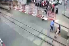 Hai nhân viên gác chắn dũng cảm quên mình cứu cụ bà thoát chết ngay trước khi đoàn tàu lao tới. (Ảnh: Trích từ camera an ninh)