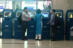 Nhân viên Vietnam Airlines hướng dẫn khách làm thủ tục trực tuyến tại kiosk check-in. (Ảnh: Việt Hùng/Vietnam+)