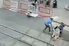 Cụ bà vấp ngã và được nhân viên gác chắn dũng cảm kéo ra khỏi đường ray đúng lúc đoàn tàu lao tới. (Ảnh: Trích từ camera an ninh)