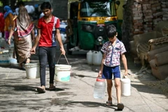 Các em nhỏ lấy nước tại điểm cấp nước công cộng ở New Delhi, Ấn Độ. (Ảnh: AFP/TTXVN)