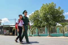 Em Huỳnh Văn Vương được Trung úy Nguyễn Đình Đức, Đội trưởng Đội Vận động Quần chúng Đồn Biên phòng Tống Lê Chân, đưa đến lớp. (Ảnh: Giang Phương/TTXVN)