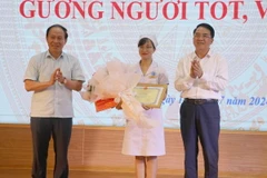 Bí thư Thành ủy Hải Phòng Lê Tiến Châu (trái) và Phó Chủ tịch Ủy ban Nhân dân thành phố Hải Phòng Lê Khắc Nam tặng Bằng khen cho điều dưỡng viên Nguyễn Thị Thảo. (Ảnh: Hoàng Ngọc/TTXVN)
