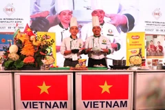 Chuyên gia cắt tỉa Phạm Văn Đông và đầu bếp Nguyễn Văn Thông giới thiệu sản phẩm được chế biến trực tiếp tại Lễ hội Ẩm thực Việt Nam. (Ảnh: Ngọc Thúy/TTXVN)