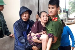 Lực lượng công an huyện Con Cuông giúp dân chuyển đến nơi an toàn. (Ảnh: Bá Hậu/TTXVN)